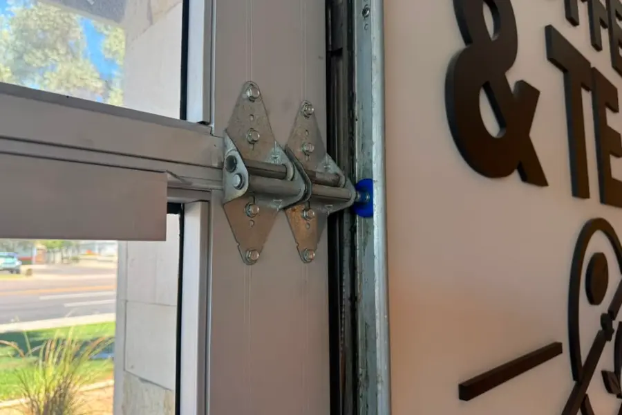 A roller and hinge bracket at the top of a commercial overhead door