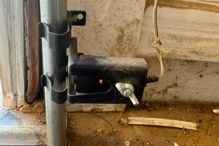 Garage door safety sensor mounted at the foot of the track on a Chandler door