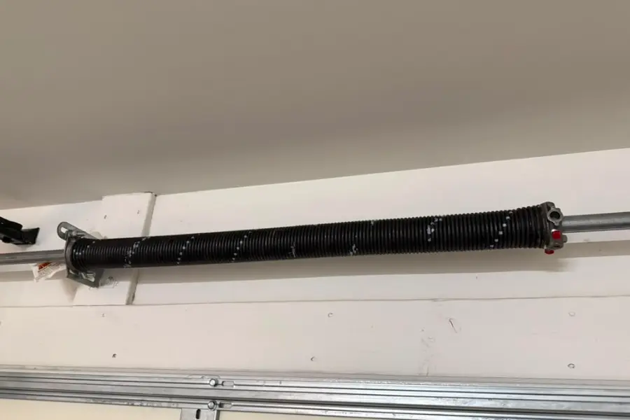 A close view of a torsion spring on the shaft at the centre bracket above a garage door