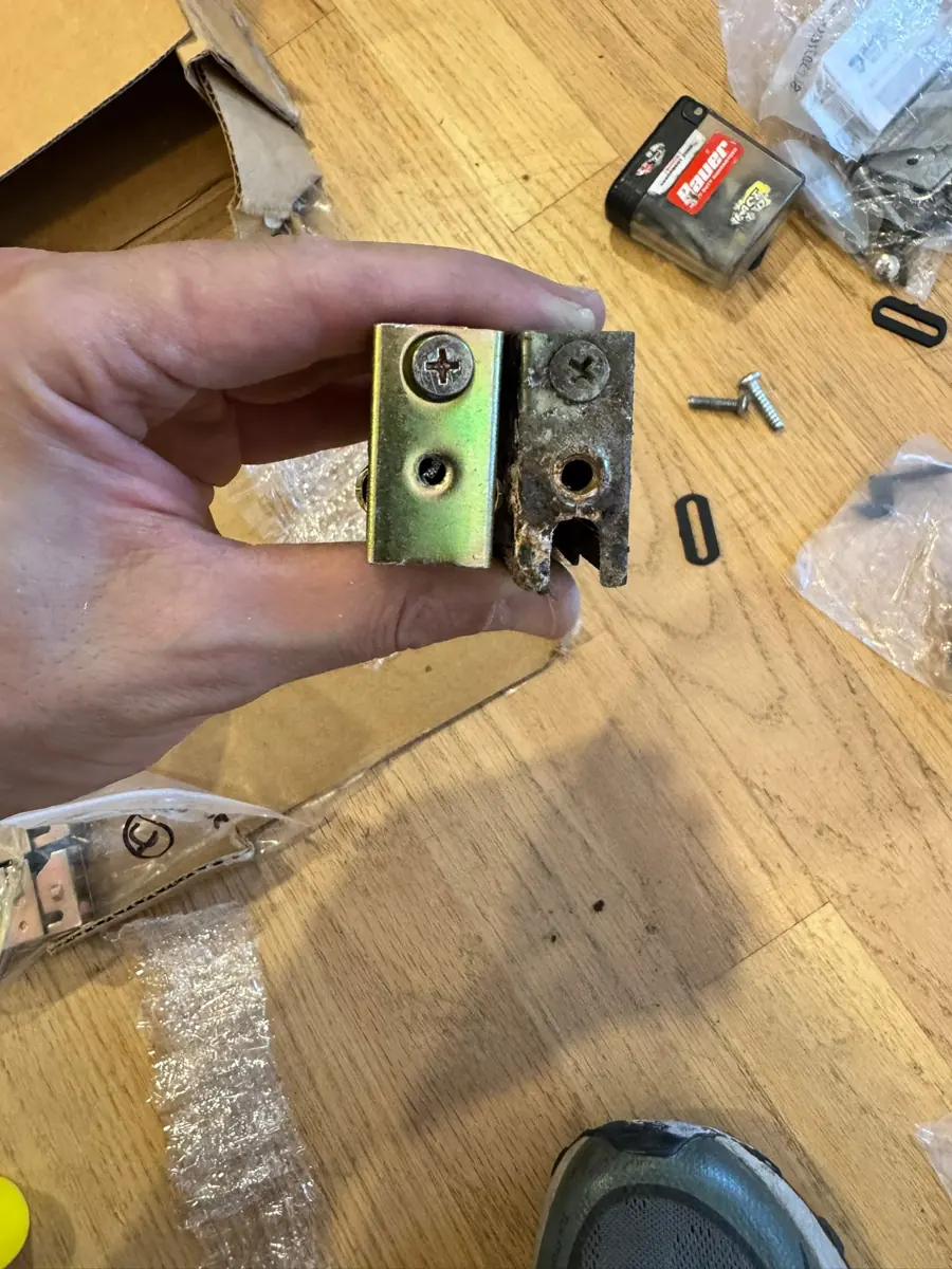 A new patio door roller assembly held next to the corroded one it replaces